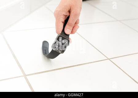 Ostfildern, Germany - July 31, 2016: A middle aged woman (only the hand is visible) is picking up a broken Apple Watch after it Stock Photo