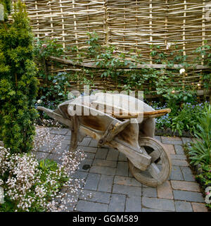 Equipment - Old-fashioned wheelbarrow and tools  with woven fencing in the background   TAS008311 Stock Photo