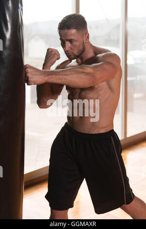 Young Man Boxing On Bag - Boxing In A Gym - The Concept Of A Healthy Lifestyle - The Idea For The Film About Boxing Stock Photo