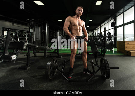 Young Man Standing Strong In The Gym And Flexing Muscles - Muscular Athletic Bodybuilder Fitness Model Posing After Exercises Stock Photo