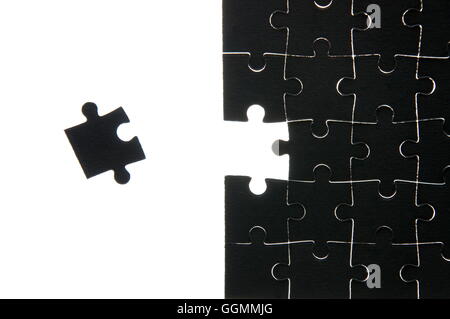 Assembled black puzzle without one element lying near him on a white background Stock Photo
