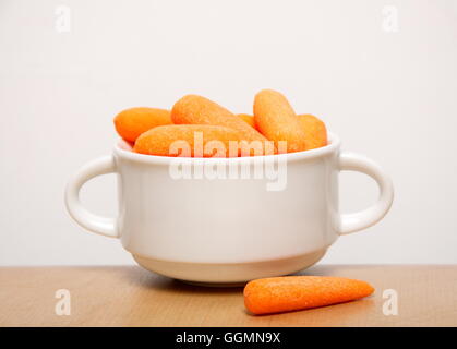 Fresh baby carrots in a white bowl on  background Stock Photo