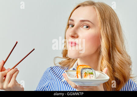 fun young girl eating sushi on white background Stock Photo