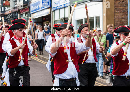 Traditional English folk dancers, Victory Morris, wearing 18th century sailor costumes, dancing as they march through town street during parade. Stock Photo