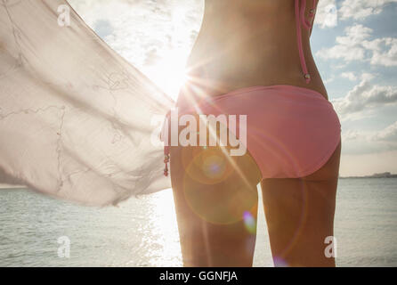 Caucasian woman in bikini holding fabric at beach Stock Photo