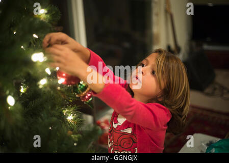 Caucasian boy hanging ornament on Christmas tree Stock Photo
