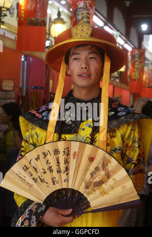 A young man dressed in period costume drums up business at a souvenir shop. Qianmen Street, Beijing – China. Stock Photo