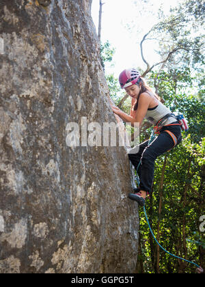 Mixed Race girl climbing rock Stock Photo