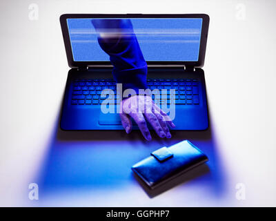 Hand of hacker reaching for wallet from screen of laptop Stock Photo