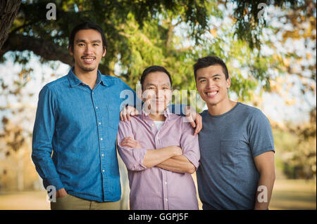 Chinese father and sons smiling outdoors Stock Photo