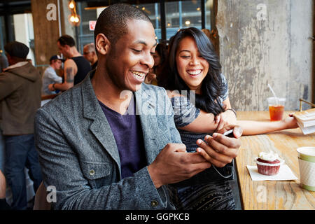 Couple using cell phone in cafe Stock Photo