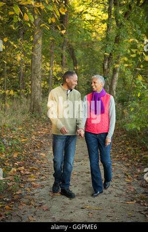 Older couple holding hands walking in forest Stock Photo