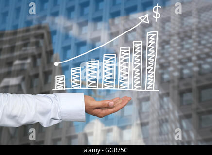 Drawing graphics growing graph on hand to concept of investment profit in business and have skyscraper background. Stock Photo