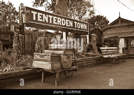 Sepia toned image of old travel cases on cart on platform of Tenterden station, Kent and East Sussex Railway. Stock Photo