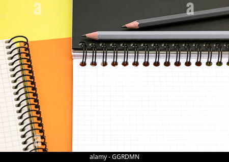 graphite pencils, open multicolor notebooks on yellow surface background closeup Stock Photo