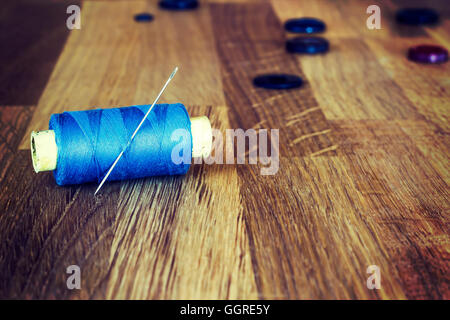 Old sewing tools on the wooden background: spools, needles, buttons. Horizontal composition. Stock Photo