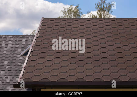 Part of red bitumen tiles roof in sunny day Stock Photo