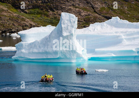 Tourists sailing in small boats on ocean sea close to large Icebergs from Tunulliarfik ice fjord in summer 2016. Narsaq, Southern Greenland Stock Photo