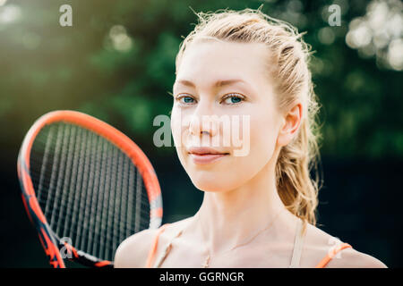 Smiling Caucasian woman holding tennis racket Stock Photo