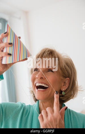 Older Caucasian woman wearing party hat Stock Photo