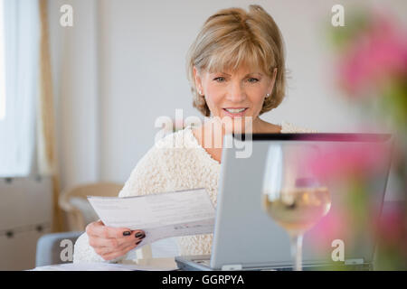 Older Caucasian woman paying bills using laptop Stock Photo