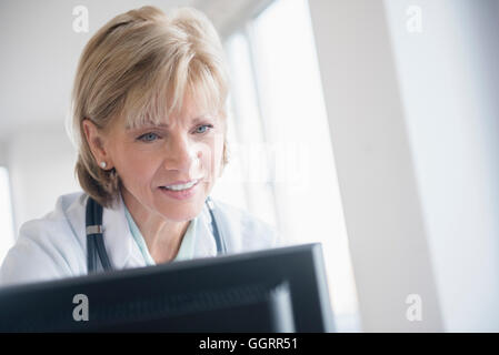 Older Caucasian doctor using computer Stock Photo