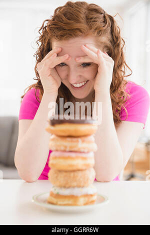 Caucasian woman resisting pile of donuts on plate Stock Photo