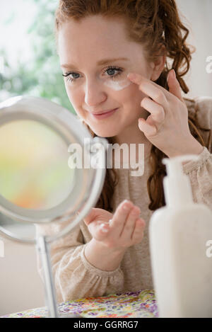 Caucasian woman applying moisturizer to face Stock Photo