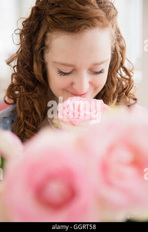 Caucasian woman smelling pink rose Stock Photo