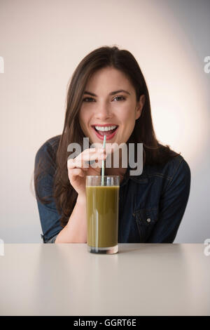Caucasian woman drinking green smoothie with straw Stock Photo