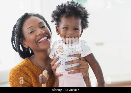 Smiling Black mother holding baby daughter Stock Photo