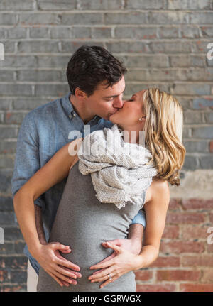 Caucasian man hugging and kissing expectant mother Stock Photo