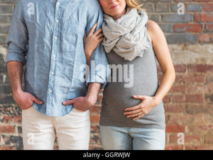 Smiling Caucasian expectant mother holding arm of man Stock Photo