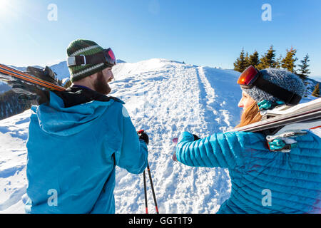 Couple carrying skis on snowy mountain Stock Photo