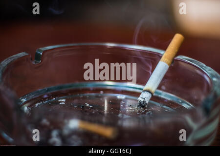 Burning cigarette in an ashtray Stock Photo