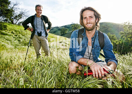 Caucasian hikers resting in grass on mountain Stock Photo