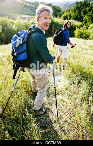 Caucasian men hiking in grass on mountain Stock Photo