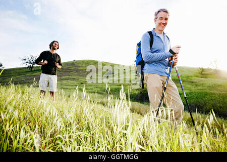 Caucasian men hiking in grass on mountain Stock Photo