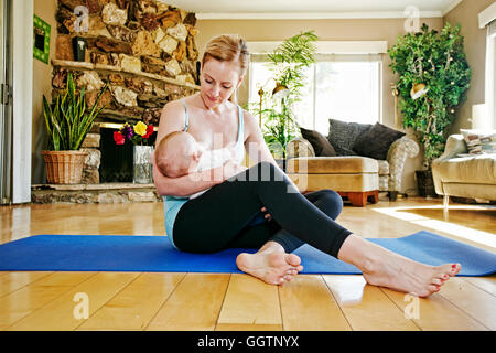 Mother resting from working out breastfeeding baby Stock Photo