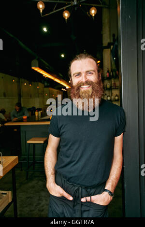 Smiling Caucasian man with beard leaning in doorway Stock Photo