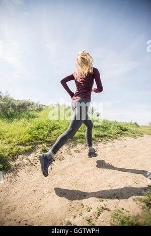 Caucasian woman running on dirt path Stock Photo
