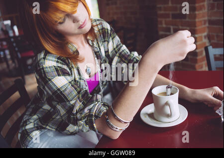 Caucasian woman sprinkling sugar in coffee Stock Photo