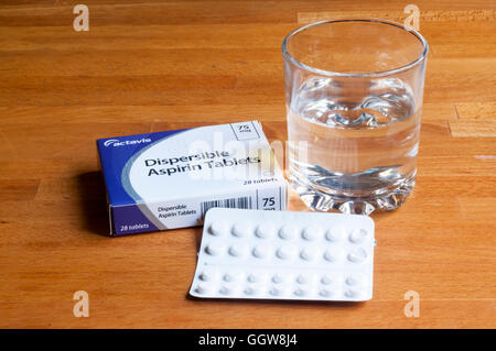 A packet of dispersible aspirins with a glass of water on a bedside table. Stock Photo