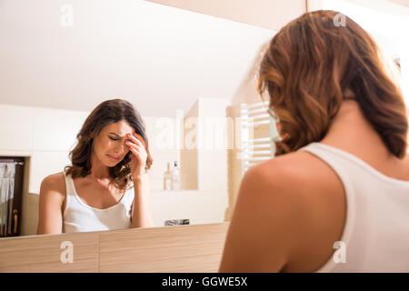 A beautiful young woman being sad at the mirror in the bathroom Stock Photo