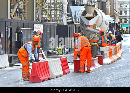Hard hat workman London building construction site adjust road barriers for cement mixer ready mixed concrete delivery truck new Scalpel building UK Stock Photo