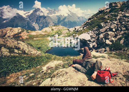 Traveler Man laying relaxing with backpack Travel Lifestyle concept serene view mountains landscape on background adventure Stock Photo