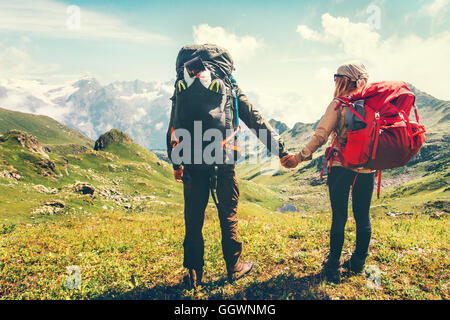 Couple Man and Woman Travelers with backpack holding hands hiking Travel Lifestyle active vacations concept mountains landscape Stock Photo