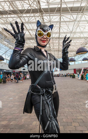 A young woman dressed in all black with large cat like ears and extra large white framed and cat shaped yellow lens glasses. Stock Photo