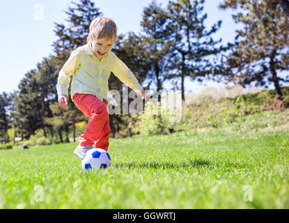Happy young boy playing football outdoors Stock Photo