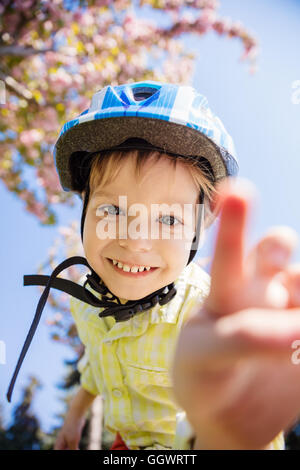 Young boy in helmet looking at camera and going to touch it Stock Photo